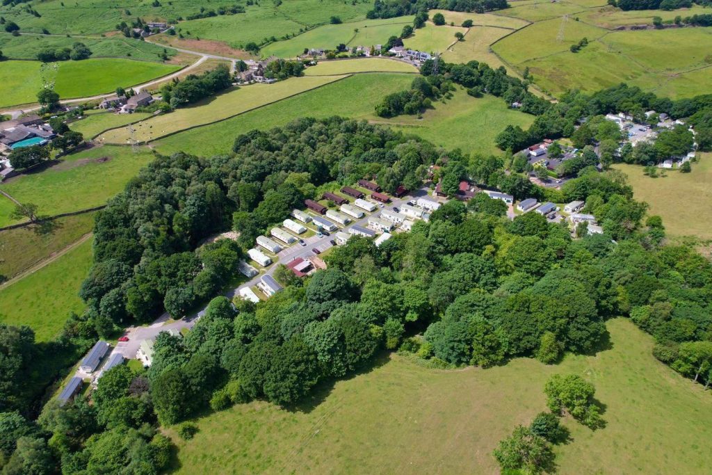 Aerial view of Moor Valley Country Park in Hawksworth, West Yorkshire, showing holiday lodges surrounded by green countryside and woodland.